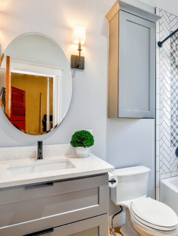 white bathroom with grey cabinets a white wc and a circle mirror